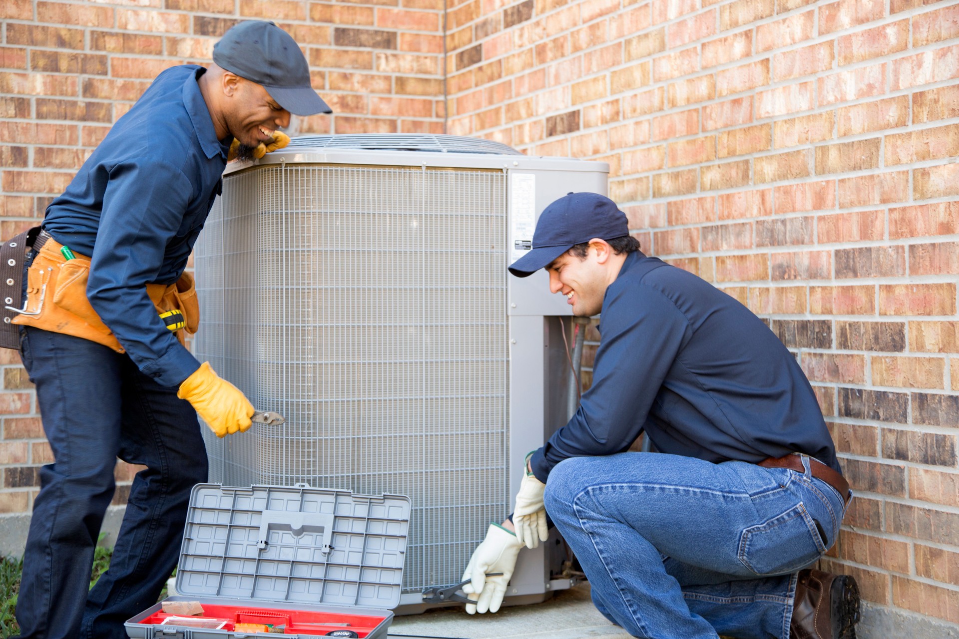 Multi-ethnic team of blue collar air conditioner repairmen at work.