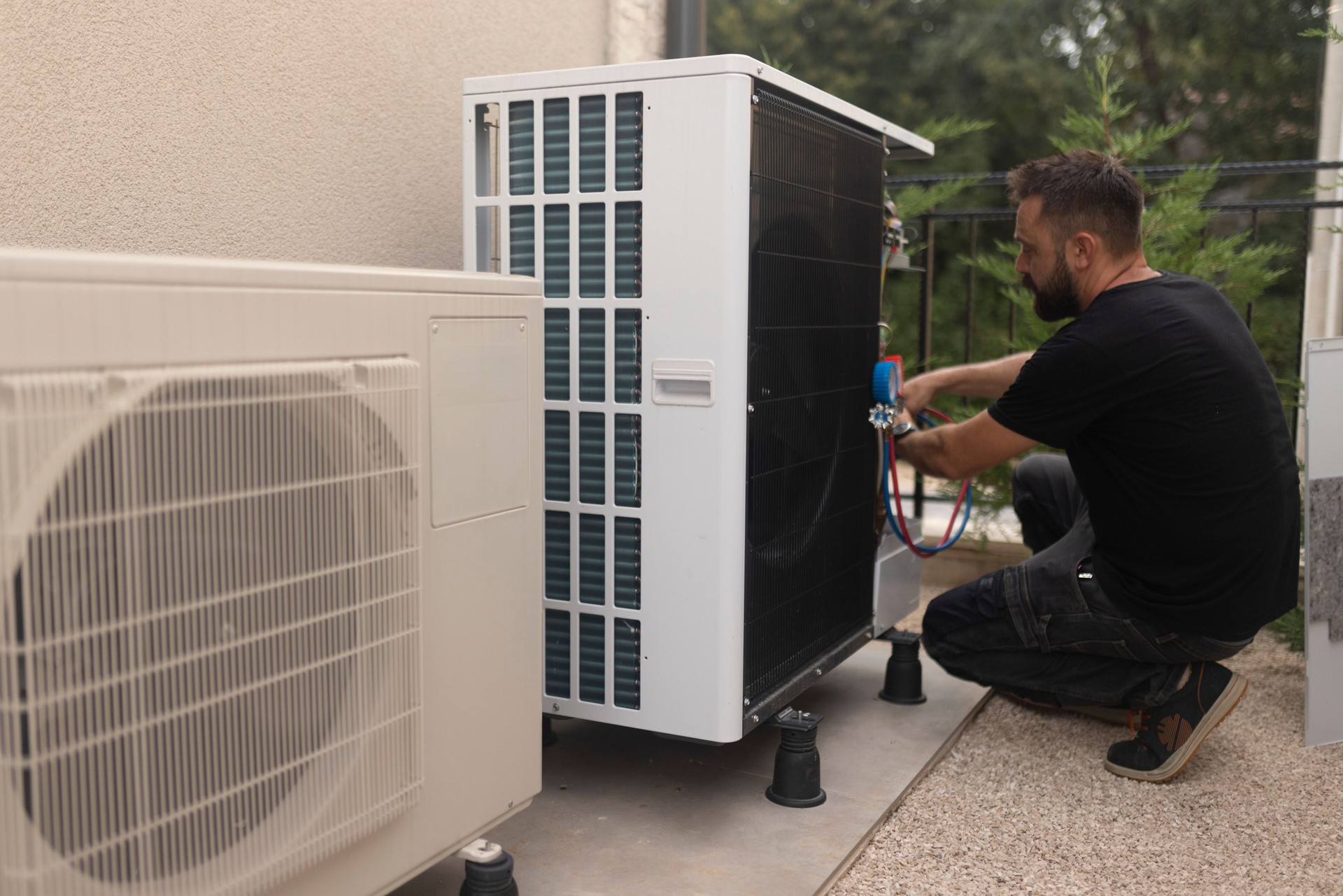 Focused electrician installing a heat pump in the yard, which is very good for households because it increases energy savings